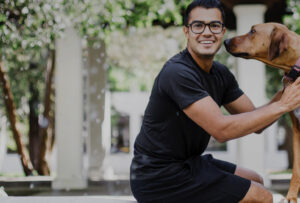 Mann sitzt auf Stein und sein Hund steht vor ihm und blickt ihn an