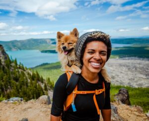 Frau bei Wanderung in den Bergen mit Hund im Rucksack.