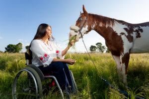 Frau im Rollstuhl füttert Pferd