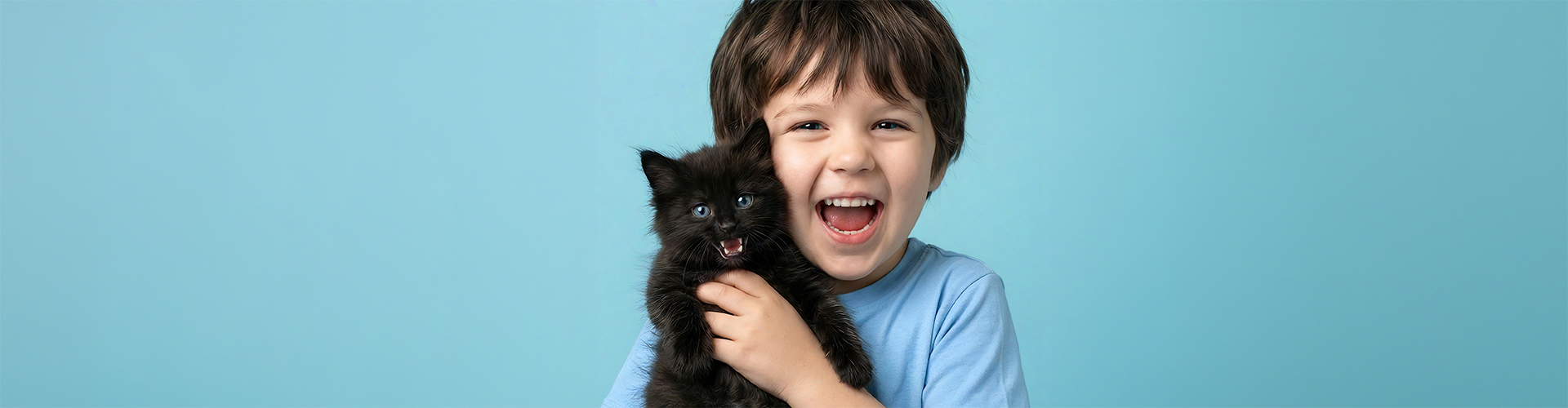 Ein kleiner Junge hält eine schwarze Katze