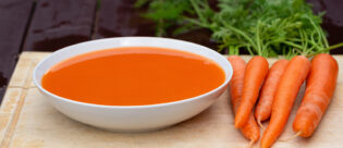 Morosche Karottensuppe mit Karotten auf Küchenbrett