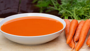 Morosche Karottensuppe mit Karotten auf Küchenbrett