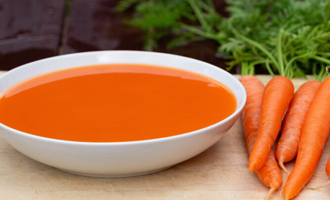 Morosche Karottensuppe mit Karotten auf Küchenbrett