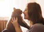 Frau kuschelt mit Katze, Haustiere wirken sich oft auf die Gesundheit aus.