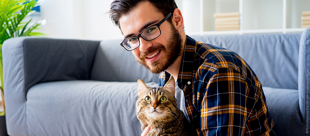 Katze schmust mit Besitzer in Wohnung vor Couch