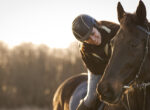 Reitende Frau beugt sich zum Pferd herunter: Richtig Pausen machen beim Pferdetraining ist wichtig.