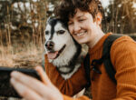 Eine Frau fotografiert sich und ihren Hund mit einem Handy.