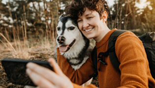 Eine Frau fotografiert sich und ihren Hund mit einem Handy.
