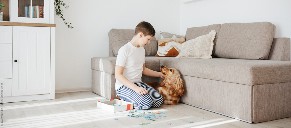 Junge puzzlet im Wohnzimmer mit seinem Hund