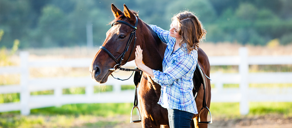 Frau steht mit einem Pferd auf der Weide