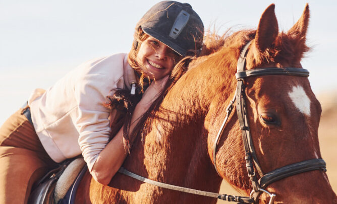 Mädchen sitzt lachend auf einem Pferd. Erfüllt sie das Bild eines Pferdemädchens?