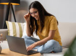 Junge Frau nimmt am Laptop Unterricht bei einer Online-Reitschule.