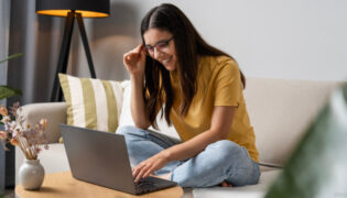 Junge Frau nimmt am Laptop Unterricht bei einer Online-Reitschule.
