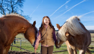 Mädchen mit zwei Pferden in den Reiterferien.