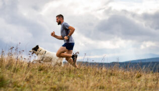 Mann joggt mit Hund.