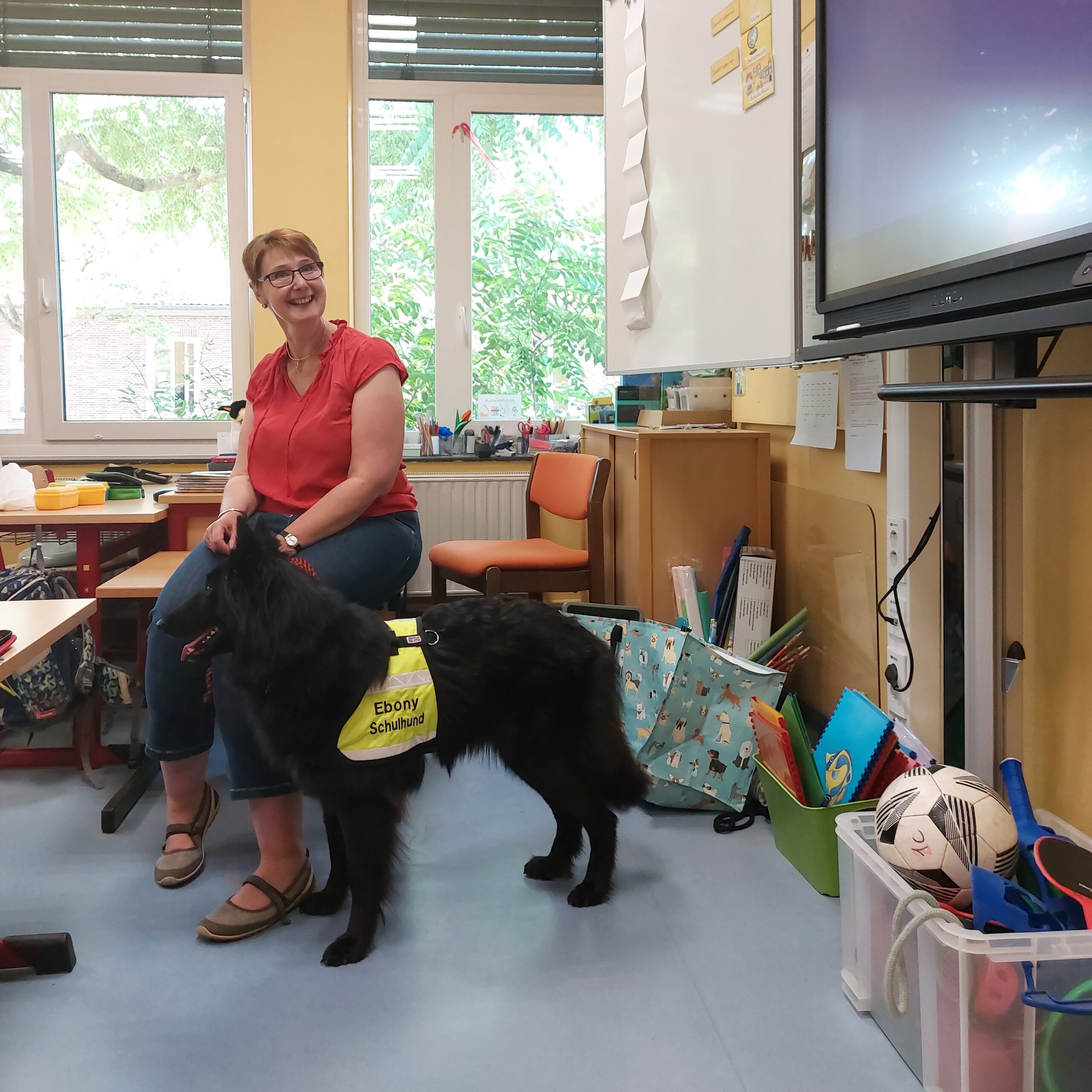Lehrerin im Klassenraum mit Schulhund.
