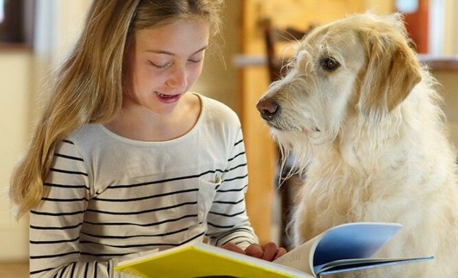 Mädchen liest. Neben ihr ein Schulhund.