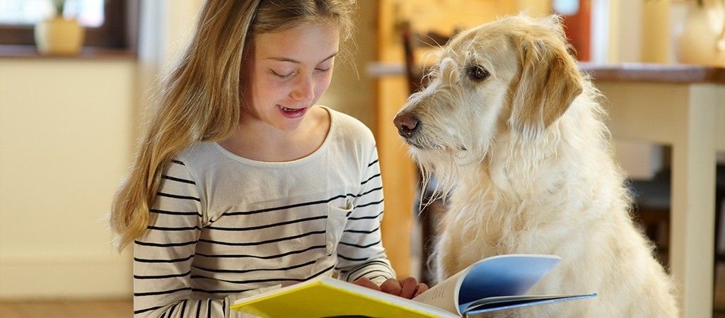 Mädchen liest. Neben ihr ein Schulhund.