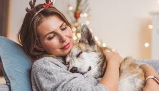 Frau kuschelt mit Hund auf Sofa