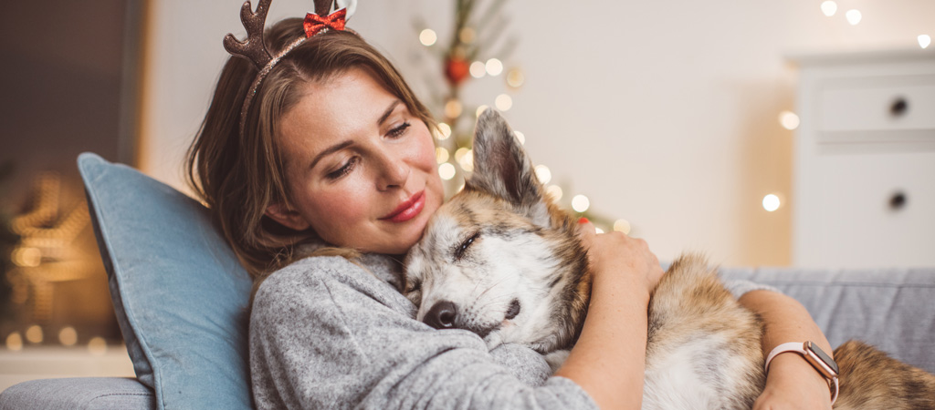 Frau kuschelt mit Hund auf Sofa