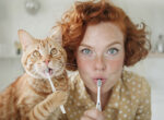 Frau mit Katze beim Zähneputzen