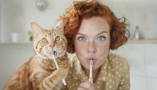 Frau mit Katze beim Zähneputzen