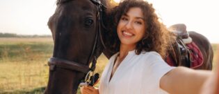 Eine junge Frau macht ein Selfie mit ihrem Pferd in natürlicher Umgebung.