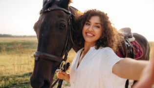 Eine junge Frau macht ein Selfie mit ihrem Pferd in natürlicher Umgebung.