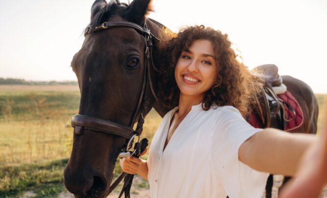Eine junge Frau macht ein Selfie mit ihrem Pferd in natürlicher Umgebung.